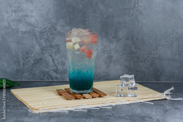 Fototapeta Refreshing fruit punch with vibrant blue hues, sparkling soda, and mixed fruit cubes. Served chilled, this drink blends tropical flair and fruity sweetness for any occasion.