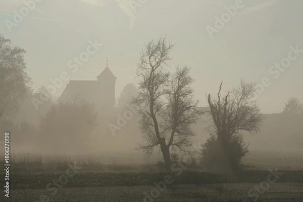 Obraz Morgendlicher Nebel mit Baum und einer Kirche im Hintergrund