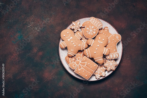 Fototapeta Gingerbread cookies in a plate on a dark rustic background, top view, flat lay, copy space, Christmas gingerbread set