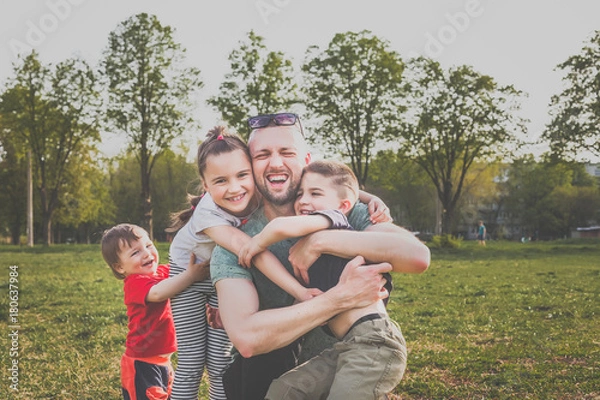 Obraz father with three children having fun in the park. hipster style. casual clothes. concept of happy family