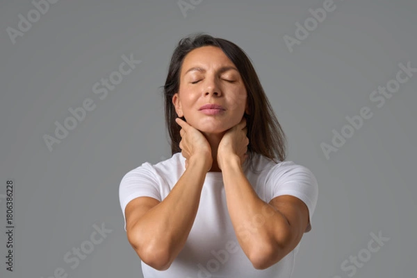 Fototapeta Calm woman closing eyes and holding neck gently expressing relief and relaxation