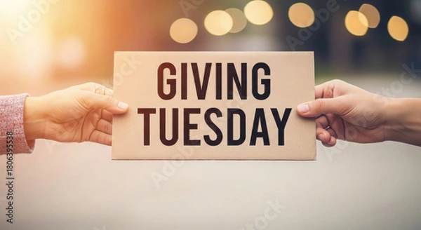 Fototapeta Hands holding a sign that says giving tuesday with bokeh lights in the background