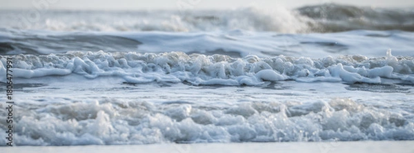 Fototapeta Waves crash gently on the shore during tranquil morning light by the sea