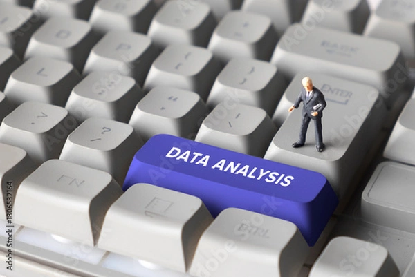 Fototapeta Miniature Businessman Standing on Keyboard Button with Text Data Analysis. Representing analytics, data processing, business intelligence and digital transformation