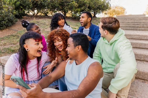 Obraz Diverse friends laughing and sharing phone outdoors