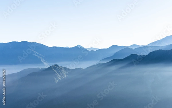 Obraz Hazy blue mountains of Zhushan inside Alishan Recreation Area in Taiwan covered by fog during sunrise in morning with bright winter sky.