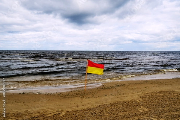 Fototapeta Drapeau d'avertissement rouge et jaune marquant la limite de la zone de baignade surveillée.