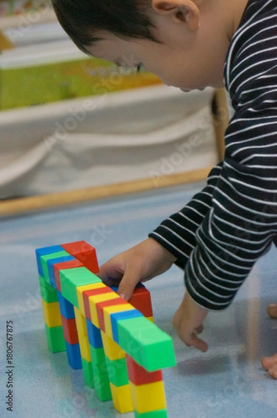 Obraz A child's hands building a structure using colorful blocks. This scene highlights creativity, learning, and play with colorful blocks.