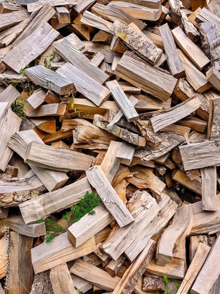 Fototapeta Close-up view of a pile of split firewood with rough bark, natural textures, and warm wooden tones. Detailed arrangement of chopped logs ready for burning. 