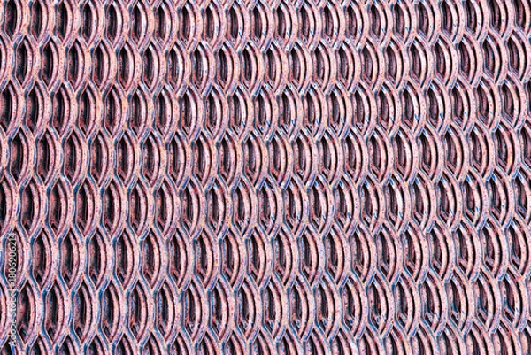 Fototapeta close-up view of a textured metal surface with a repeating pattern of oval shapes. The color is a mix of red and silver tones, creating a modern industrial look
