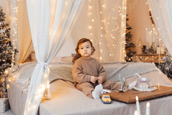 Fototapeta Little boy playing with a toy. Child is sad sitting on the bed.