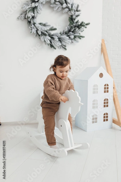Fototapeta Little boy playing with toy horse. Child swinging on a rocking horse on a white background