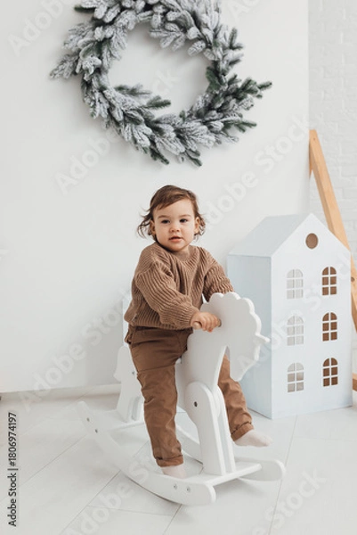 Fototapeta Little boy playing with toy horse. Child swinging on a rocking horse on a white background