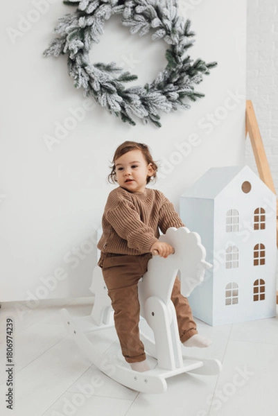 Fototapeta Little boy playing with toy horse. Child swinging on a rocking horse on a white background