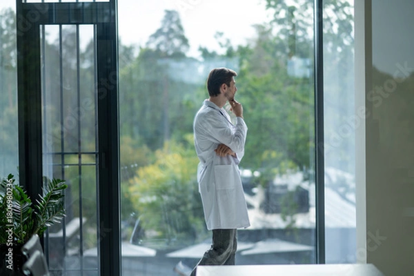 Obraz Male doctor looking thoughtfully out of window