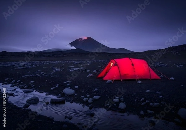 Fototapeta Illuminated red tent set up in volcanic landscape under a dark moody sky
