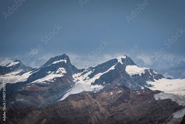 Fototapeta Cloudy day over the Swiss Alps, viewed from Glacier Paradise in Zermatt, with dramatic peaks and misty alpine scenery