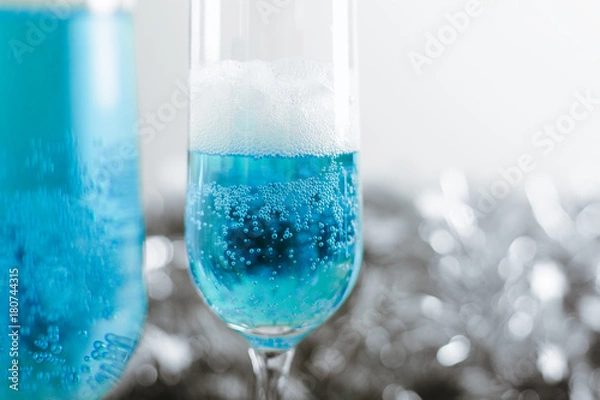 Fototapeta Two glasses with cold light blue champagne on white background with silver decoration. Side view horizontal. Close-up, copy space