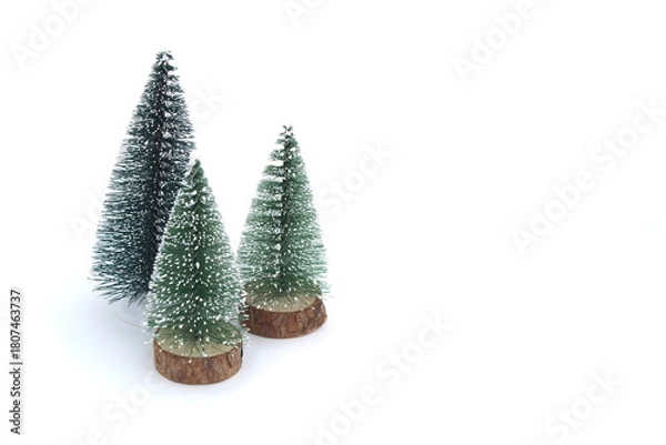 Fototapeta On a white background there are three small decorative Christmas trees.