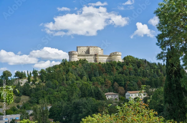 Obraz The imposing Forte di San Leo (San Leo Fortress) perched on a steep, forested hill in Italy.