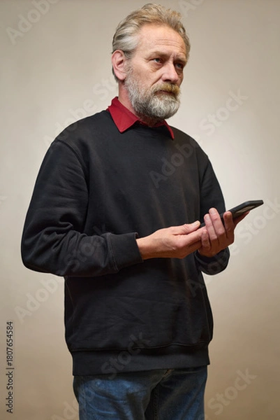 Fototapeta Old man over 60 portrait in studio with smartphone