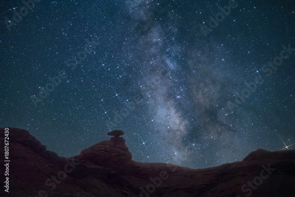 Fototapeta Mexican Hat, Utah and the landscape that gives the town its name. Red rock formation of Mexican Hat highlighted by the milky way
