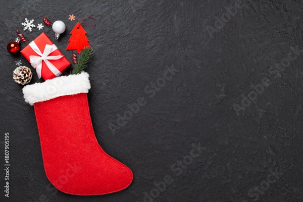 Fototapeta Christmas sock with gifts and decoration on concrete background, top view