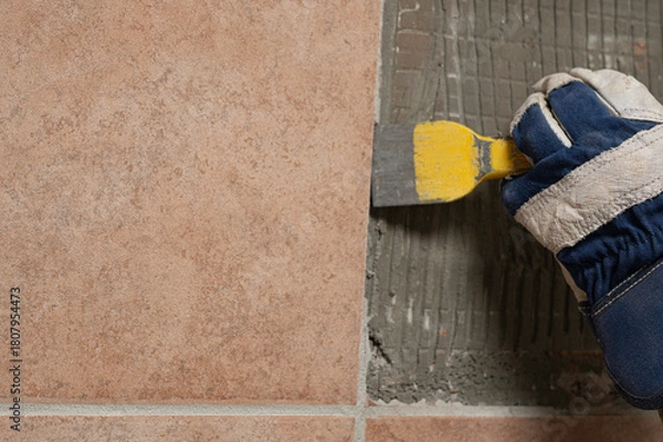 Fototapeta Denmark, november 2025, glove with chisel hammering tiles down