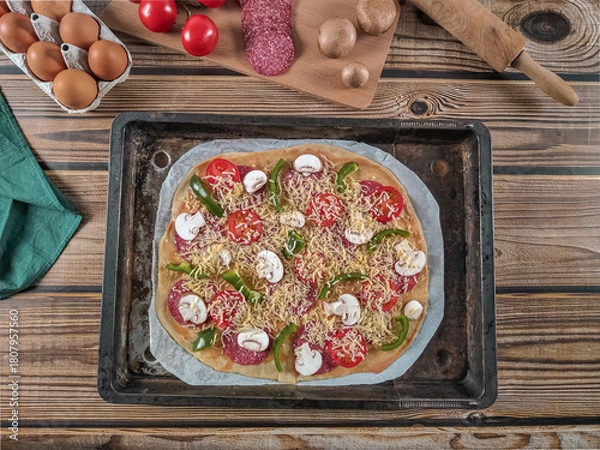 Fototapeta Step 15. Raw pizza with fresh ingredients in one baking dish on a wooden table.