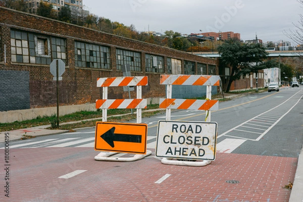 Fototapeta Road closure signs block traffic in urban area on a cloudy day