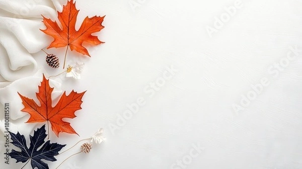 Obraz A flat lay composition featuring vibrant orange maple leaves, dark blue leaves, pinecones, and delicate white flowers against a white background with soft fabri