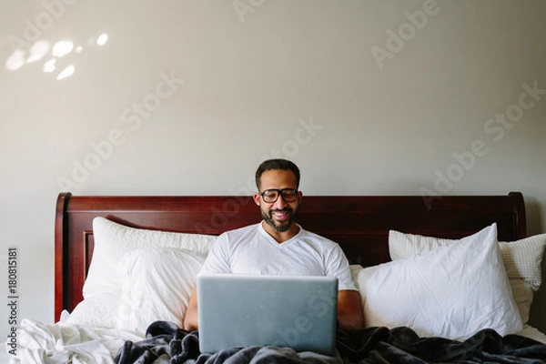 Obraz Black man working in bed with laptop computer