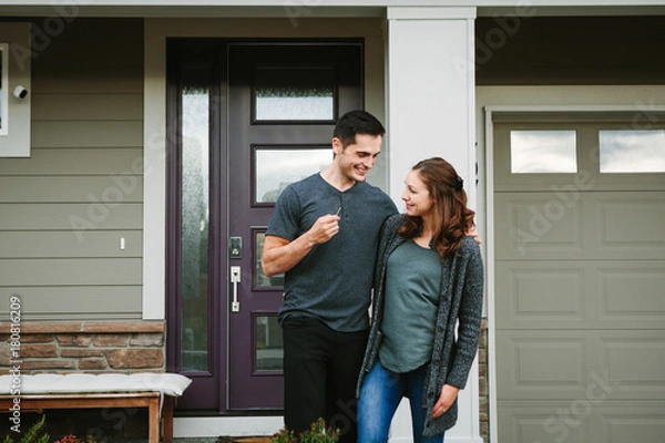 Obraz Young couple holding keys in front of new home