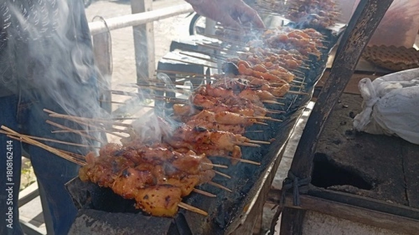Obraz Traditional Sate Ayam being Cooked on Skewers | Smoking Barbecue of Indonesian Street Food | Marinated Chicken Skewers on a Grill