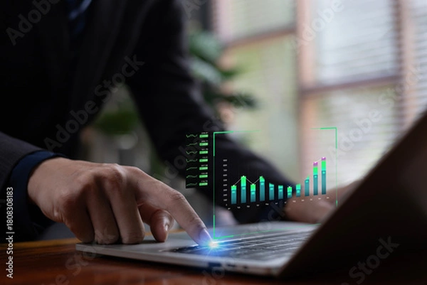 Fototapeta A business professional interacting with digital bar charts and financial metrics on a laptop, representing data analytics, financial growth insights, and modern business intelligence technology.