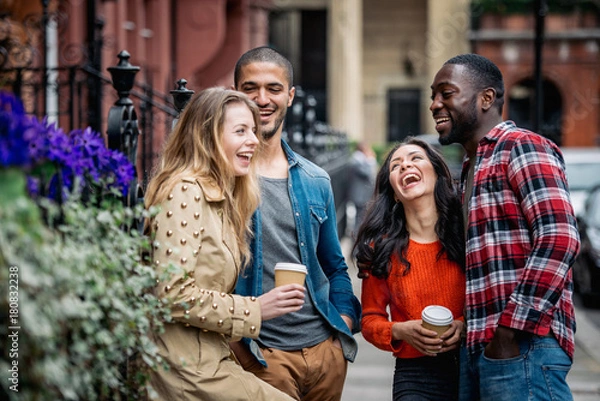 Obraz Multiracial group of friends having fun together in London. Two girls and two boys, talking and laughing. Residential district with houses and cars on background. Lifestyle and friendship concepts.