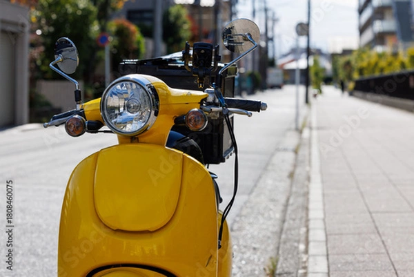 Fototapeta 道路に止まっている宅配用の黄色いオートバイ
