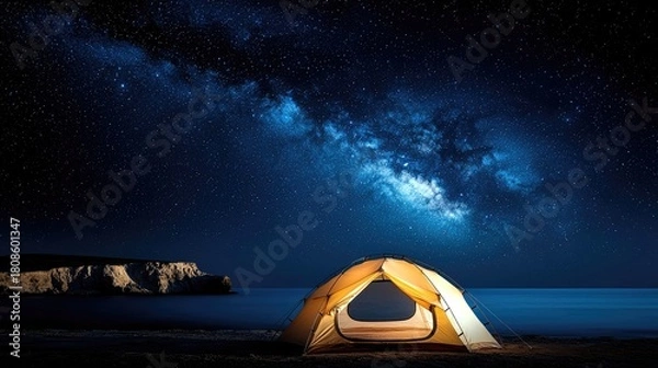 Obraz A glowing tent sits on a dark beach beside the ocean, beneath a vast expanse of stars and the Milky Way.