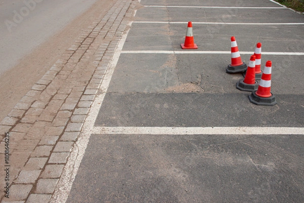 Fototapeta Traffic cones positioned on an empty parking lot, with clear lines and a smooth asphalt surface, creating a structured and organized environment for vehicle management