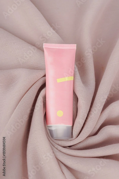 Fototapeta The tone-up cream is placed on a soft cream-colored fabric, creating a warm and elegant look