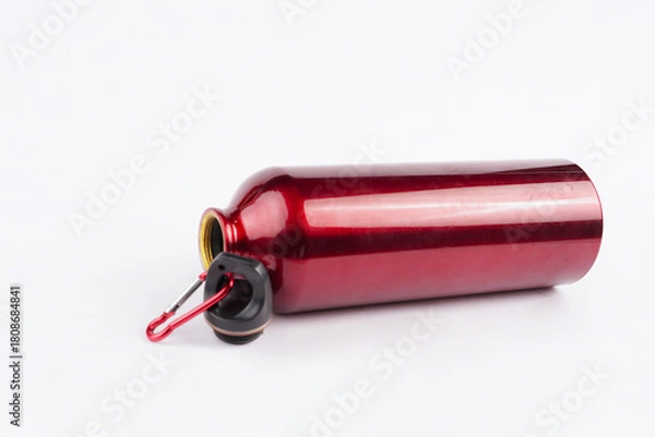 Fototapeta The red drinking bottle is placed on a clean white background, creating a striking contrast