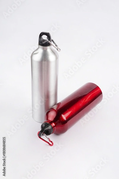 Fototapeta Two drinking bottles, one gray and one red, are placed on a clean white background