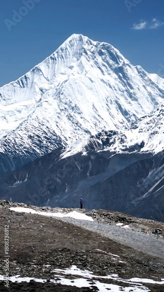 Obraz Lone Hiker Under Majestic Snowcapped Mountain Peak with Clear Blue Sky