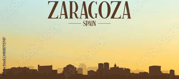 Fototapeta Panoramic poster of the city skyline with misty background buildings, hills sunrise, sunset and clouds of ZARAGOZA, SPAIN
