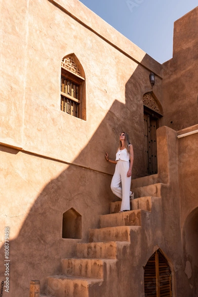 Obraz Woman exploring traditional omani architecture enjoying sunlight