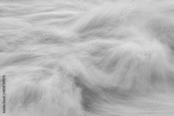 Fototapeta Monotone long-exposure view of moving water forming soft swirling patterns and blurred textures