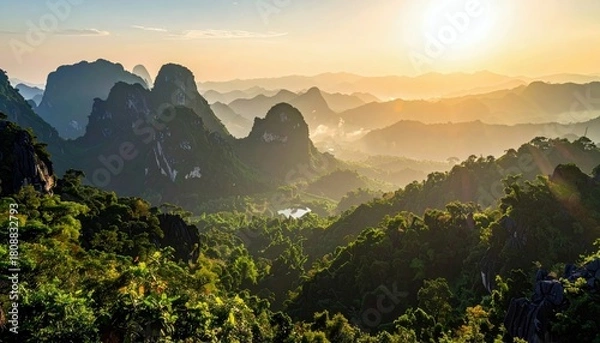 Fototapeta A breathtaking panoramic view of a misty mountain range bathed in the golden light of sunrise, with dense green forests covering the slopes and a small lake nes