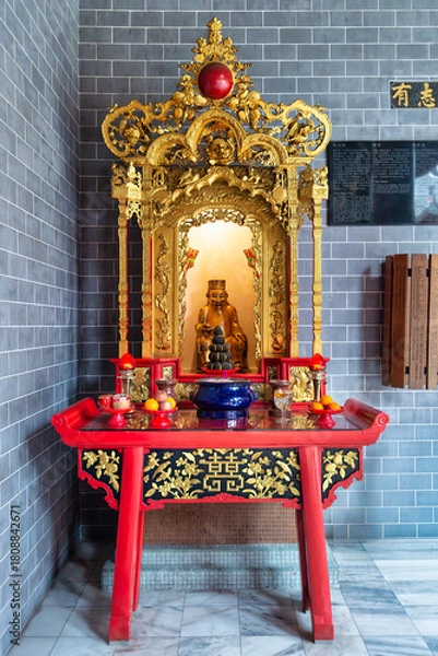 Fototapeta Ornate golden shrine with a statue, offerings, and red altar table inside Chan She Shu Yuen Ancestral Hall, Kuala Lumpur, Malaysia. Traditional Chinese cultural interior