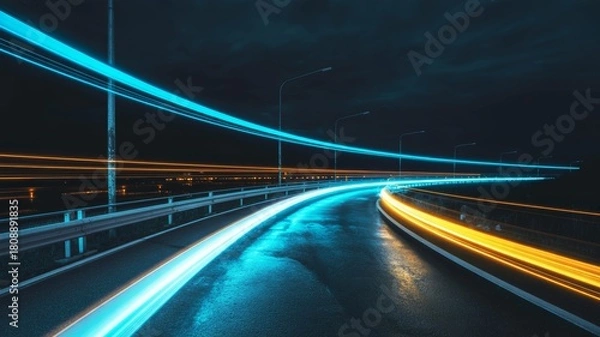 Fototapeta A dynamic night scene capturing light trails on a wet road, showcasing vibrant blue and orange hues against a dark sky.