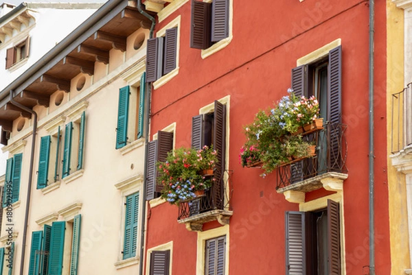 Fototapeta Cozy balcony in Verona, an Italian town with warm architecture and charming details. Peaceful Mediterranean atmosphere, flowers, sunlight, and traditional building style